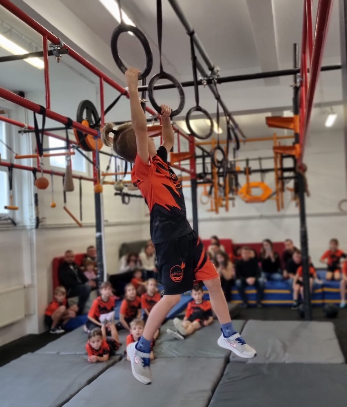 Grupa dzieci z trenerami na sali treningowej SFERA Ninja Gym